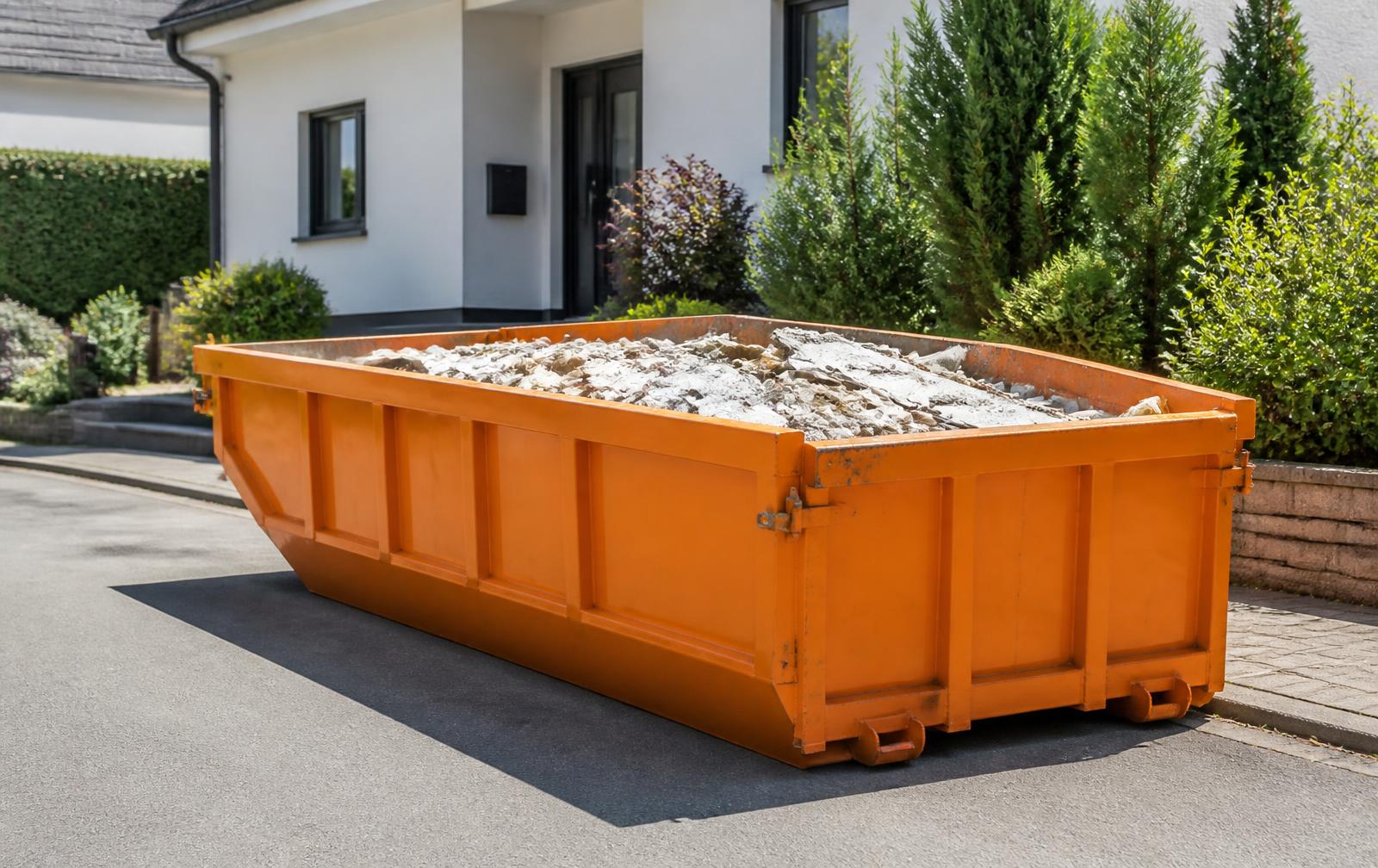 Container portocaliu pentru moloz livrat în fața unei case